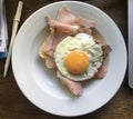 High angle close up over a plate with a sunny side up egg abd ham next to a pen