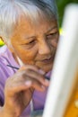 High angle close-up of serious biracial senior woman painting with paintbrush on canvas in yard