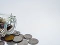 High angle close up shot of an open glass jar with coins and white background for Saving concept Royalty Free Stock Photo