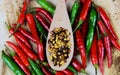 High angle close up view on isolated wood spoon with hot spicy chili flakes and raw red green chillies on natural brown wood plate Royalty Free Stock Photo