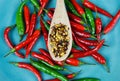 High angle close up view on isolated wood spoon with hot spicy chili flakes and raw red green chillies on scratched blue china Royalty Free Stock Photo
