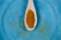 High angle close up view on isolated wood spoon with red spicy hot chili powder on scratched blue china plate Royalty Free Stock Photo