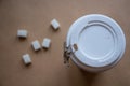 High-angle close-up view of several white sugar cubes scattered on a light beige or tan-colored surface. Royalty Free Stock Photo