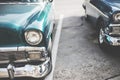 High angle closeup shot of a cyan vintage car`s headlight with a blue vintage car next to it