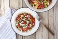 High angle closeup shot of greek salad in a metal bowl with a fork and striped napkin beside it Royalty Free Stock Photo