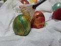 High angle closeup shot of a person coloring Easter eggs on a white fabric