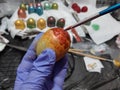 High angle closeup shot of a person coloring Easter eggs on a white fabric