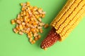 High angle closeup shot of a pile of peeled yellow corns on a green background