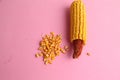 High angle closeup shot of a pile of peeled yellow corns on a pink background