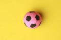 High angle closeup shot of a pink and black toy soccer ball on a yellow background Royalty Free Stock Photo