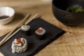 High angle closeup shot of three sushi pieces with sticks and soy sauce on a wooden table