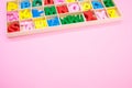 High angle of colorful wooden letters in their case, placed on a pink surface Royalty Free Stock Photo