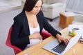 Concentrated pregnant businesswoman using laptop