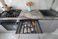 High angle frontal closeup view to open drawer of grey and white modern domestic kitchen