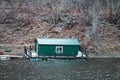 High-angle of a green house boat on the Mississippi river deciduous trees on the hillside