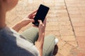 Low section of woman using phone while sitting on seat