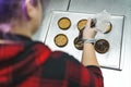 High angle perspective of professional bakery chef decorating chocolate tarts with the use of pastry bag.