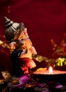 High angle photography of ganesha statue with earthen lamp on flower petals against red chunari in the background. religion and Royalty Free Stock Photo