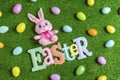 High angle of plush bunny and Easter letters banner with plastic Easter eggs