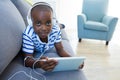 High angle portrait of boy using digital tablet while listening to headphones on sofa at home Royalty Free Stock Photo