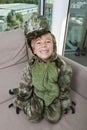 High angle portrait of happy boy in dinosaur costume sitting on sofa at home