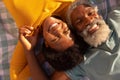 High angle portrait of smiling african american couple lying on blanket at beach on sunny day Royalty Free Stock Photo