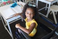 High angle portrait of smiling african american elementary girl sitting on wheelchair in classroom Royalty Free Stock Photo