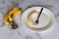 High angle shot of bananas with a fork in a white plate - preparation of banana bread