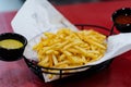 High angle shot of a basket of french fries and sauce on a red wooden table