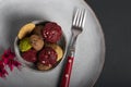 High angle shot of a beautiful grey plate with some small cookies and a red fork in it