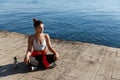 High angle shot of beautiful relaxed woman having yoga training near the sea, meditating on a pier Royalty Free Stock Photo