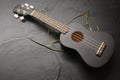 High angle shot of a black ukulele on a messy black surface