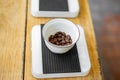 High angle shot of a bowl of coffee beans on a digital scale