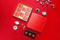 High angle shot of a box of chocolate and some miniature utensils on a red surface