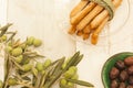 High angle shot of breadsticks in a glass bowl near green olives on a wooden surface Royalty Free Stock Photo