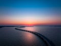 High-angle shot of a bright pink sunset on the horizon with curvy bridge going over the water Royalty Free Stock Photo