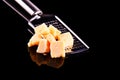 Parmesan cheese and grater on a black glossy table with reflection. Parmesan cheese isolated on black background.