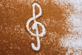 High angle shot of brown species sprinkled on a white background and musical clef on the center