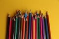 High angle shot of a bunch of colored pencils on a yellow surface