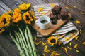 High angle shot of a cup of coffee and brownies on a table next to gorgeous sunflowers