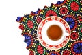 High angle shot of a cup of tea on a traditionally designed placemat on a white surface