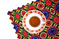 High angle shot of a cup of tea on a traditionally designed placemat on a white surface