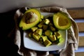 High angle shot of cut-up avocado pieces on a plate with halved avocados