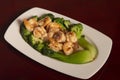 High angle shot of dish of prawns with broccoli and ham on a wooden surface
