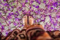 High angle shot of a female's feet on a concrete ground covered with fallen flowers petals Royalty Free Stock Photo