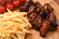 High angle shot of french fries on a wooden board with cherry tomatoes and roasted chicken on it Royalty Free Stock Photo