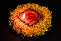 High angle shot of glowing terracotta lamp on flower petals over the black background. faith and belief concept