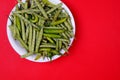 High angle shot of green beans and chili pepper on plate isolated on red background Royalty Free Stock Photo