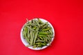 High angle shot of green beans and chili pepper on plate isolated on red background Royalty Free Stock Photo