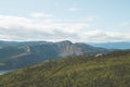 High angle shot of a green forest in the mountains near the lake under the cloudy sky Royalty Free Stock Photo